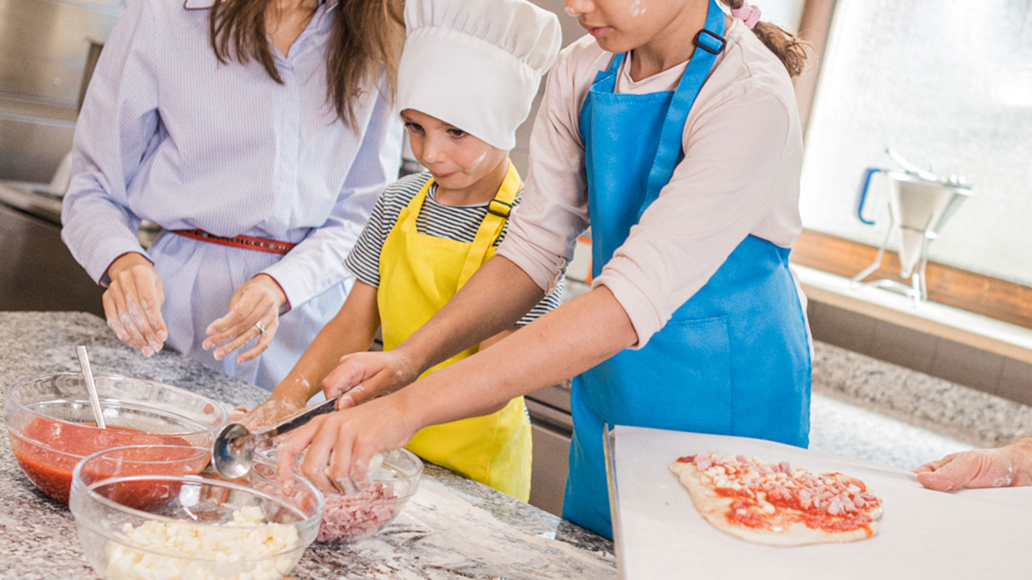 Family topping a pizza - Hotel Fameli