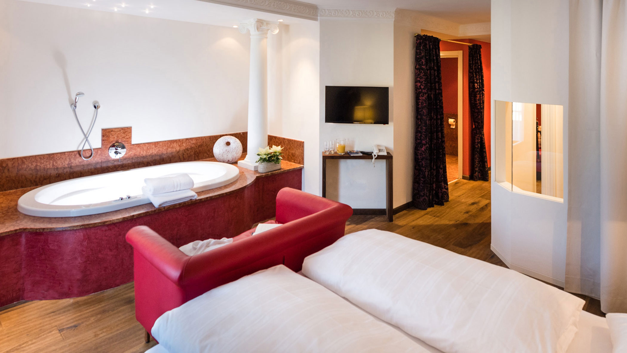 Jacuzzi Suite living room with whirlpool & red sofa - Hotel Fameli