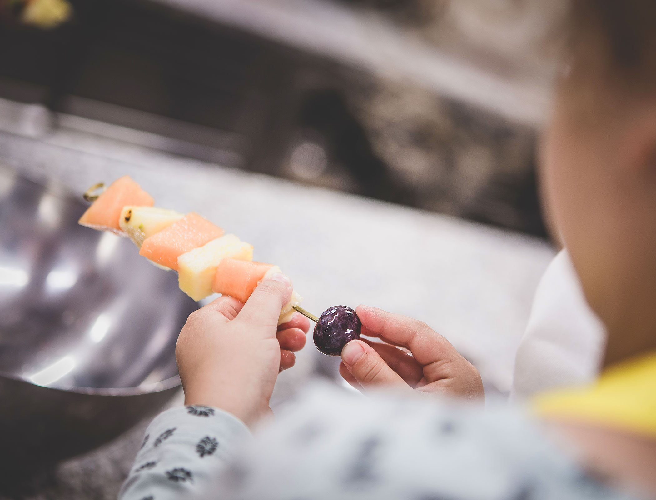 Child prepares fruit skewer - Hotel Fameli