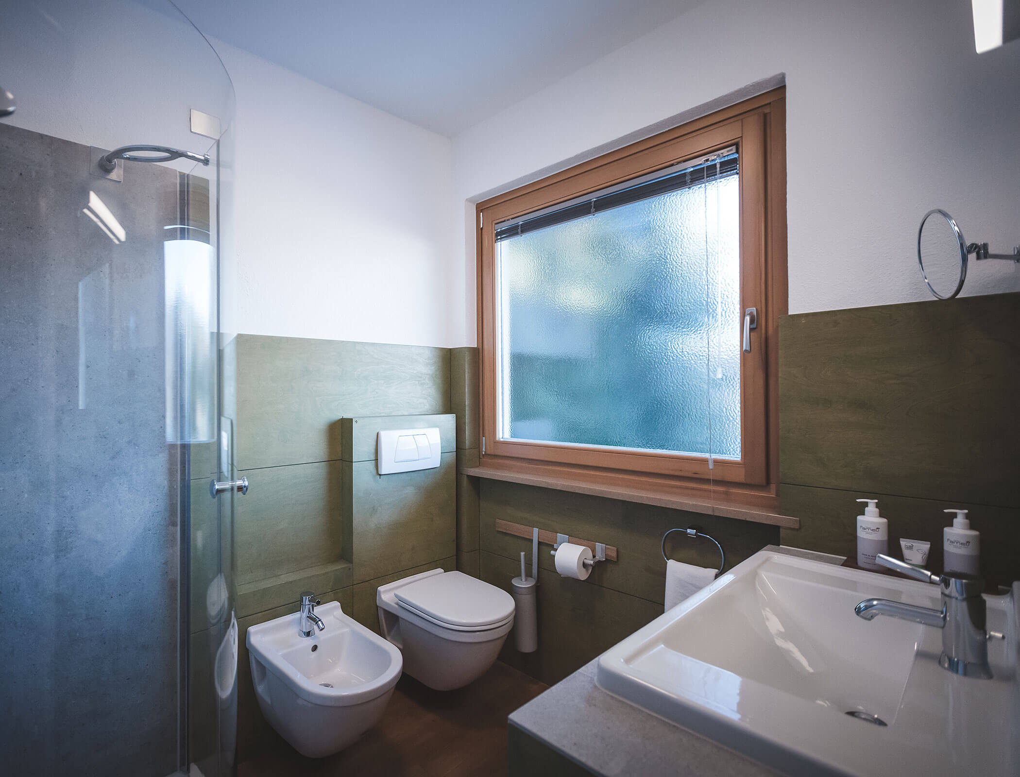Modernes Badezimmer mit Dusche, Bidet, Toilette, Waschbecken, großem Fenster und grünen Akzenten an den Wänden. - Hotel Fameli