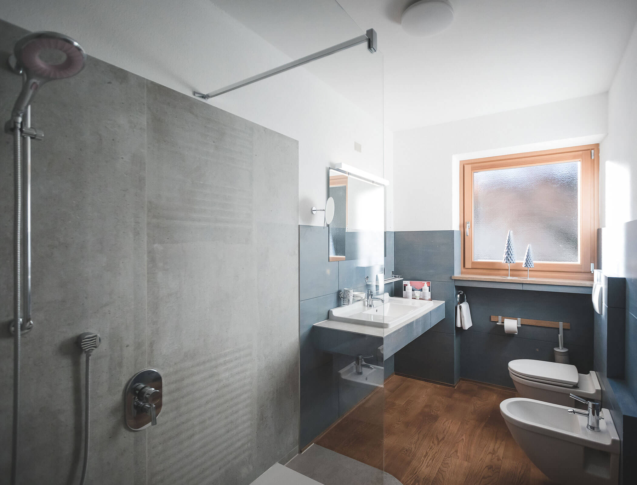 Modernes Badezimmer mit begehbarer Dusche, Waschbecken, Toilette, Bidet, Holzboden und Milchglasfenster. - Hotel Fameli