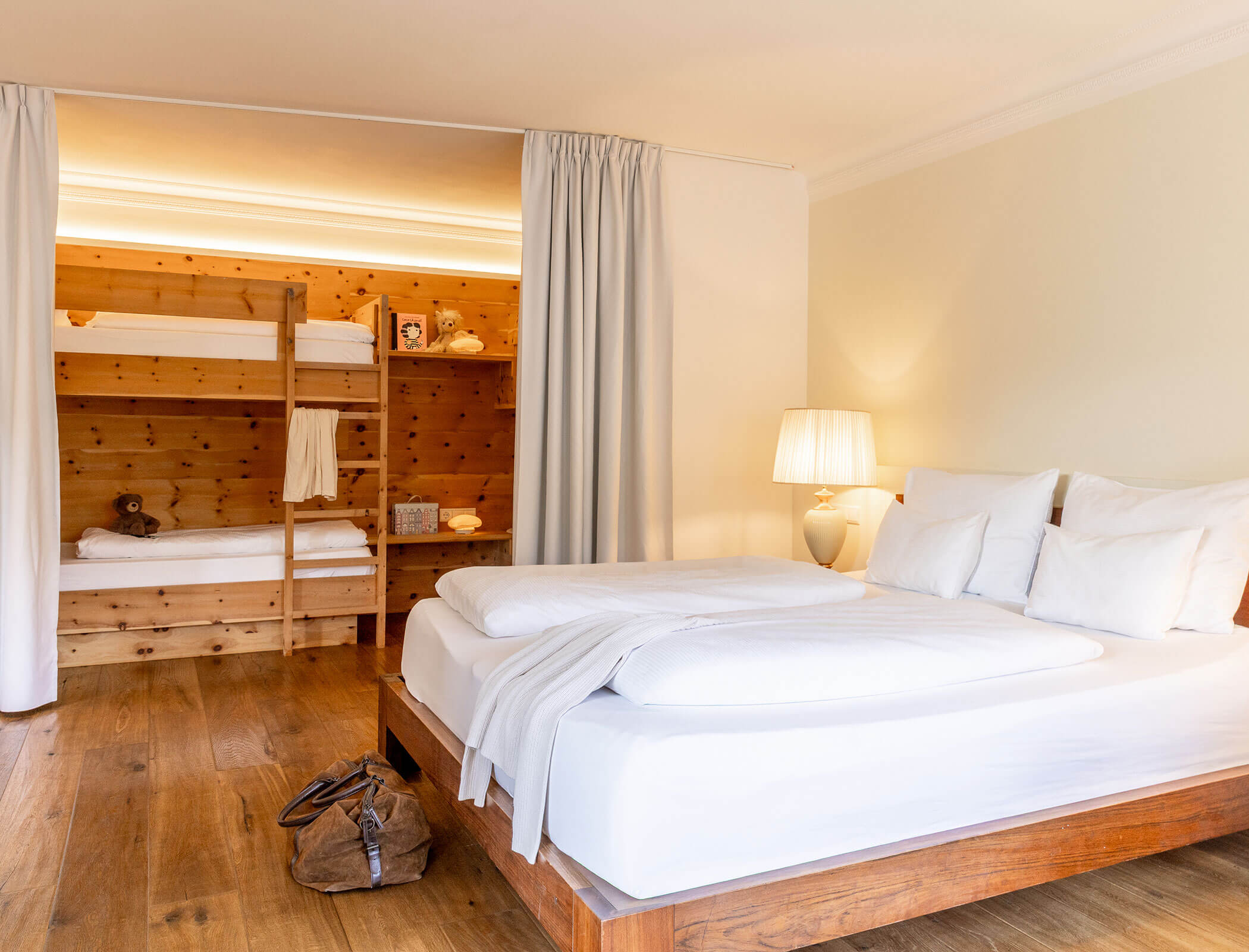 Bright bedroom with a double bed, bunk beds with wooden frame, and a lamp on a nightstand. - Hotel Fameli
