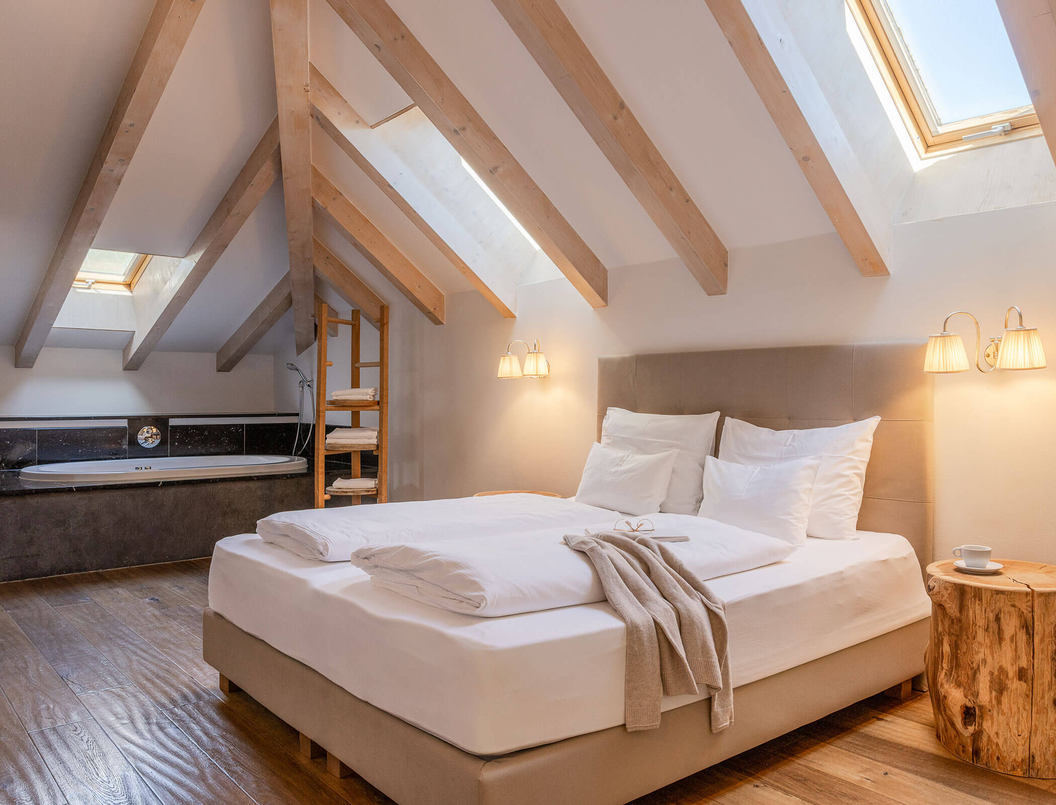 Cozy attic bedroom with wooden beams, skylights, a double bed, and a bathtub in the corner. - Hotel Fameli